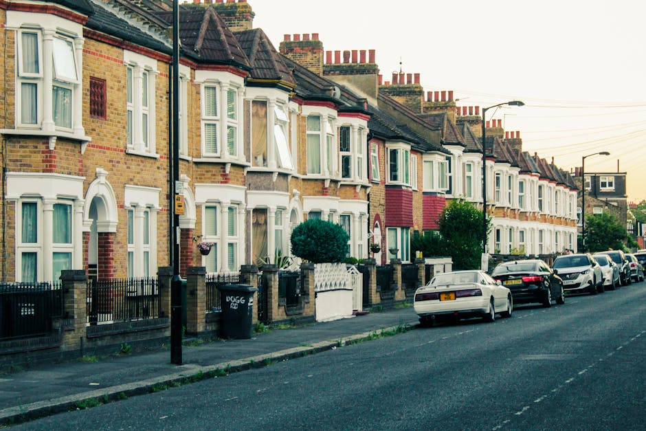 The image shows the front facade of a Victorian terrace house, with a brick exterior and two white-framed sash windows on the upper level, one partially open and the other closed. Below, there are two